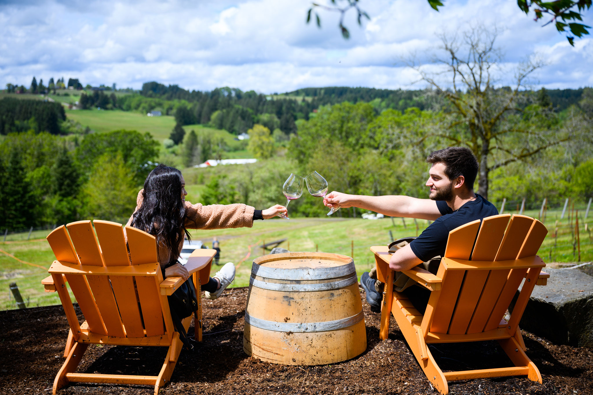 220514.mca.PRO.Wine.Hunt.116-(1) Couple clinking glasses while relaxing in adirondack chairs at an Oregon winery